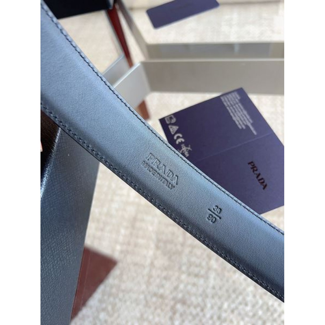 サフィアーノ調 Prada プラダ コピー ベルト ブラック型押しレザー ラウンドロゴバックル マット質感 スマートな印象 メンズ定番